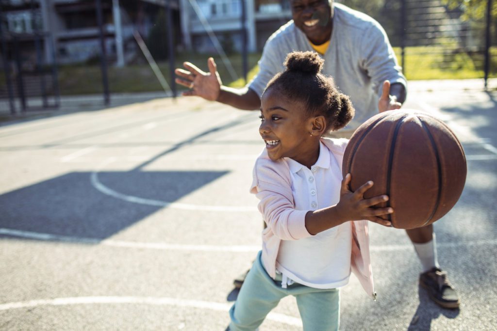 Grandfather and granddaughter playing basketball